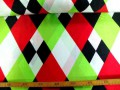 Een glanzende carnavals stof met gekleurde wiebertjes. 100% polyester  1.50 mtr. breed