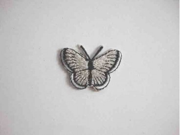 Een opstrijkbare vlinder applicatie van 3 x 2.5 cm. Lichtgrijs glitter