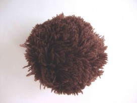 Een donkerbruin pom pom bolletje met een doorsnee van 7 cm.  Leuk voor het garneren van mutsen capes of kleding.