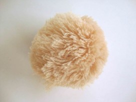 Een lichtcamel kleurig pom pom bolletje met een doorsnee van 7 cm.  Leuk voor het garneren van mutsen capes of kleding.