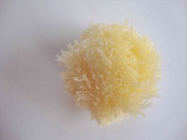 Een zachtgeel pom pom bolletje met een doorsnee van 7 cm.  Leuk voor het garneren van mutsen capes of kleding.