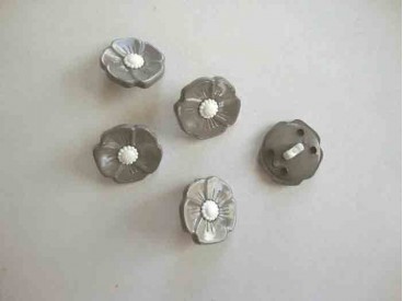 Een grijs/witte kunststof bloemknoop met een doorsnee van 15 mm.