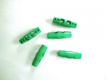 Een groene plastic 2-gaatsknoop  Ongeveer 25 mm lang