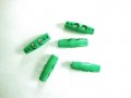 Een groene plastic 2-gaatsknoop  Ongeveer 25 mm lang
