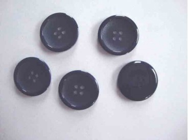 Een diep donkerblauwe ( bijna zwarte) kunststof mantelknoop met een doorsnee van 25 mm.