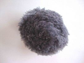 Een grijs pom pom bolletje met een doorsnee van 7 cm.  Leuk voor het garneren van mutsen capes of kleding.