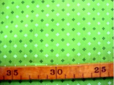 Een lime kleurige bedrukte quiltkatoen met een wit/donker lime mini patroontje. 100% katoen 1.45 mtr.br.