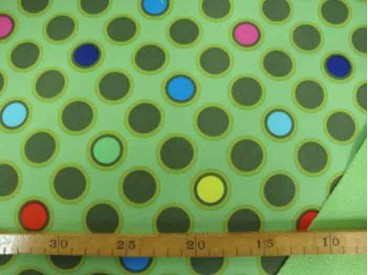Een limegroene shoftshell met diversen gekleurde cirkels. De stof is wind en waterdicht en rafelt niet. 97% Pe/3% Sp 1.45 mtr. b