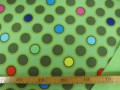 Een limegroene shoftshell met diversen gekleurde cirkels. De stof is wind en waterdicht en rafelt niet. 97% Pe/3% Sp 1.45 mtr. b